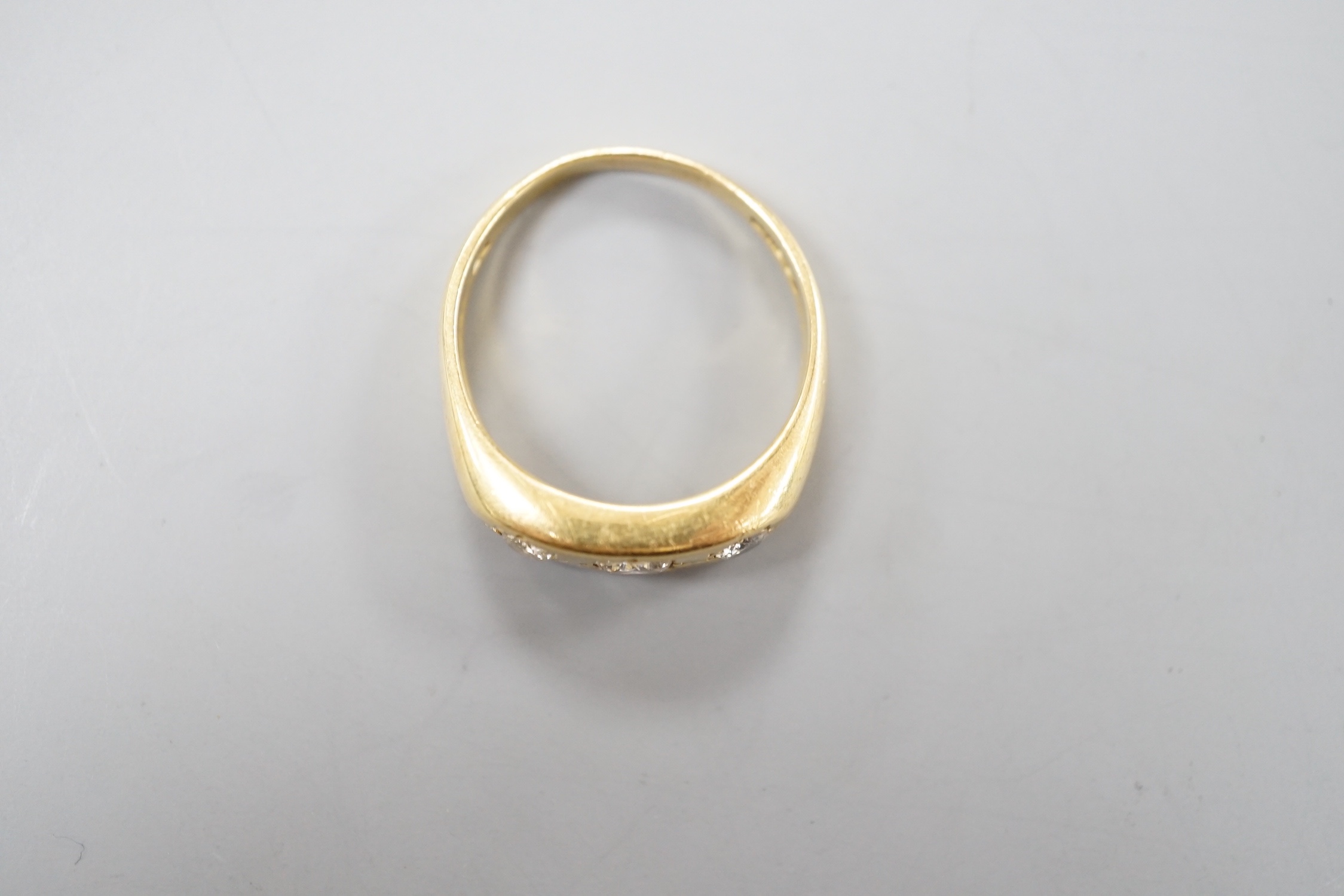 An 18ct gold and three stone gypsy set diamond ring, size S, gross weight 7.1 grams.